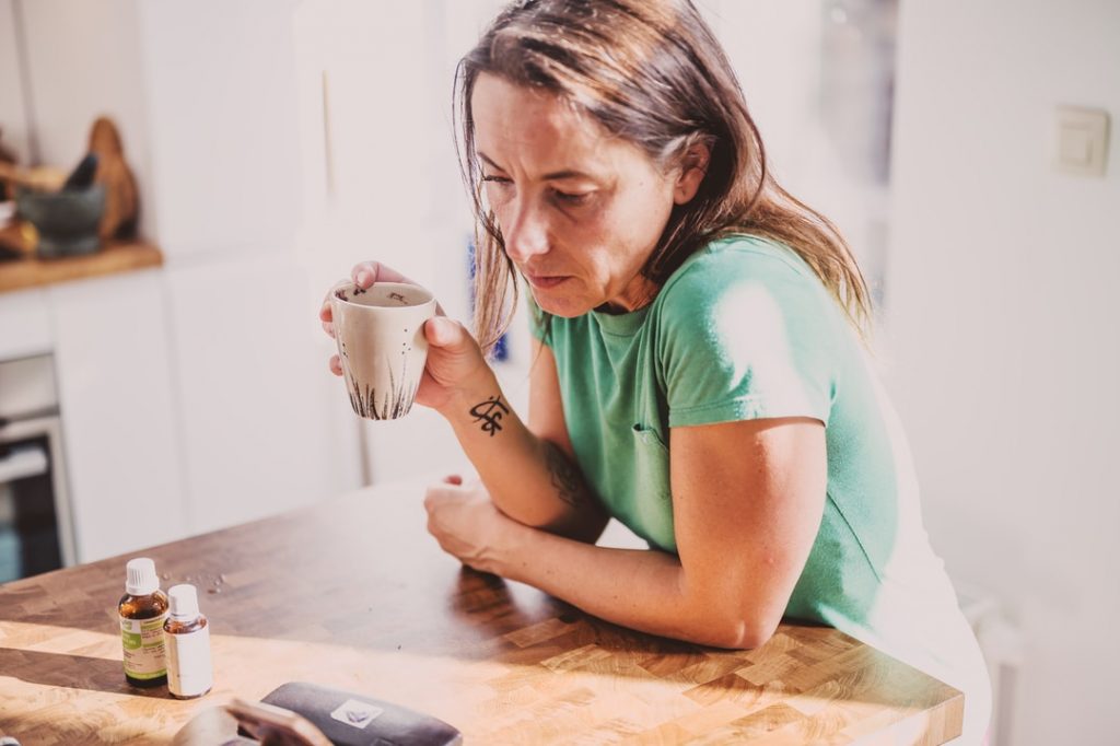 woman in green t-shirt holding white ceramic mug